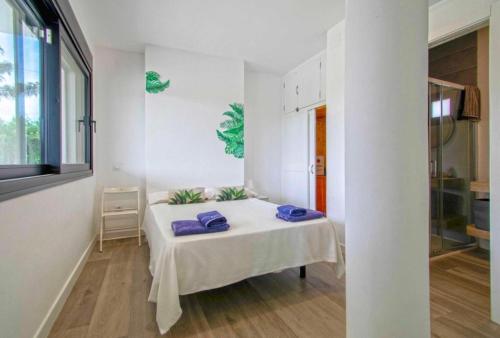 a white room with a bed with purple pillows on it at OLE TÚ ANDALUCIA in Sanlúcar la Mayor
