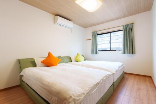a bedroom with a bed with orange and yellow pillows at Tenjinbashi-suji Shopping Street Guesthouse Entire House Direct train access to 道頓堀 黒門市場 USJ Kansai International Airport in Osaka