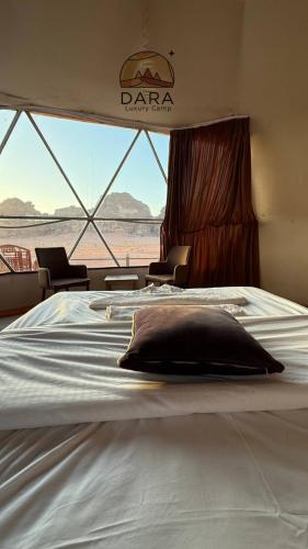 a bed in a room with a view of the desert at DARA RUM lUXURY CAMP in Wadi Rum