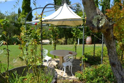 a table and a white umbrella in a garden at Borgo Casa al Vento in Gaiole in Chianti