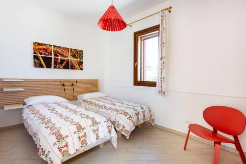 een slaapkamer met 2 bedden en een rode stoel bij Villa delle Stelle in Scopello