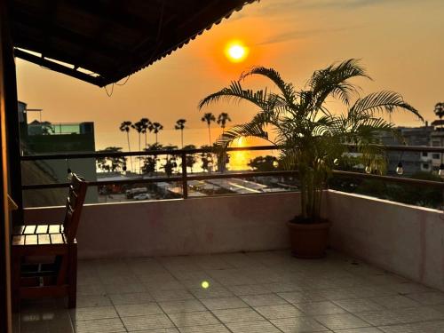 a view of the sunset from a balcony with a palm tree at Orient Hotel in Jomtien Beach