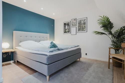 a bedroom with a bed with a blue wall at Eksklusiv 2BR lejlighed I Terrasse I Fri parkering in Odense