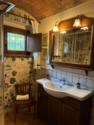 een badkamer met een wastafel, een spiegel en een stoel bij Borgo San Benedetto in Montaione