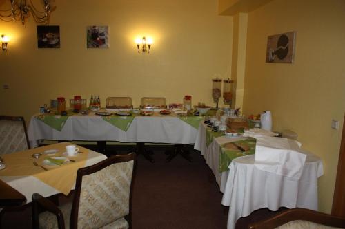 ein Esszimmer mit Tischen und weißen Tischdecken in der Unterkunft Hotel am Ring in Magdeburg