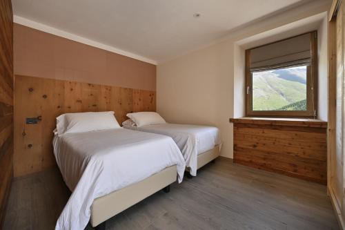 two beds in a room with a window at Ca del Tusa in Livigno