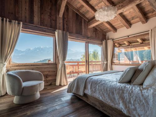 ein Schlafzimmer mit einem Bett und einem Stuhl und einem großen Fenster in der Unterkunft Chalet Marianna I Le Chalet Club in Combloux