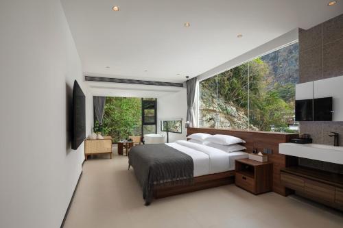 een slaapkamer met een bed en een groot raam bij Karst Scenic Hotel in Gaotian