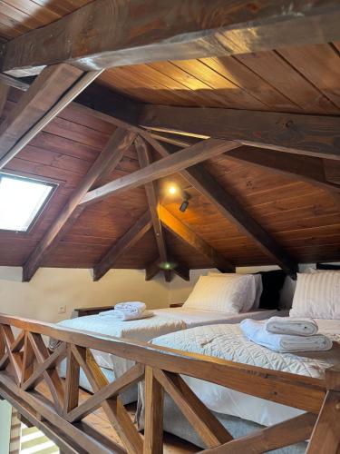 deux lits dans une chambre mansardée avec plafond en bois dans l'établissement Angie Kipos by Thanasis Papaioannou, à Evangelístria