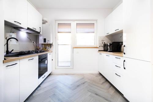 Una cocina blanca con gabinetes blancos y una ventana. en Amaria Sunrise, en Popeşti-Leordeni