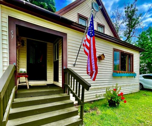 una casa con una bandiera americana sopra di Mattawamkeag River Cottage a Island Falls