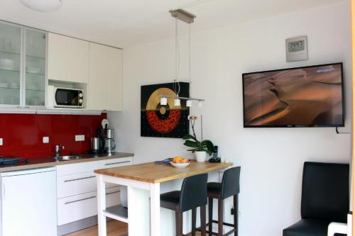 a kitchen with a table with chairs and a tv on the wall at Studio A Am Burgberg in Erlangen