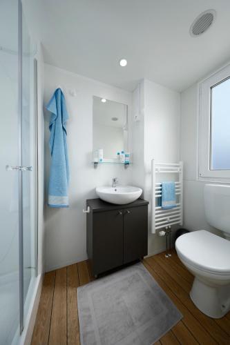 a white bathroom with a sink and a toilet at Knaus Campingpark Nürnberg in Nuremberg