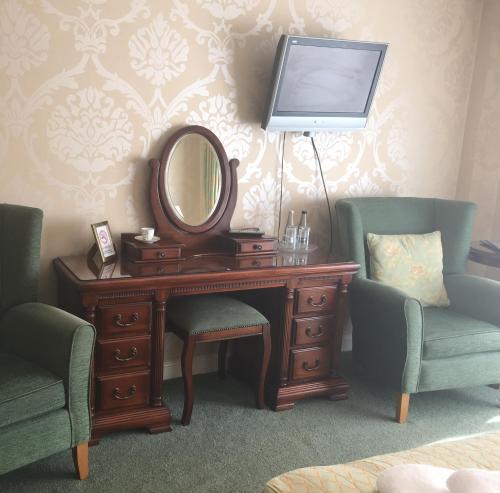 a desk with a mirror and two chairs and a television at Dunsley Hall Country House Hotel in Whitby
