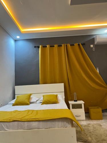 een slaapkamer met een bed met een geel gordijn bij Tataicha Stydio 1 in Ndjamena