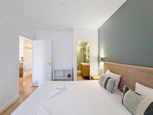 a bedroom with a large white bed and a bathroom at L'intemporel YourHostHelper in Deauville