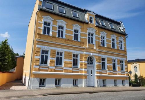 un bâtiment jaune et blanc sur le côté d'une rue dans l'établissement Alt-Berliner Schwanenhof Ferienwohnung EG rechts, à Lychen