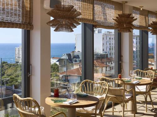 un restaurant avec des tables et des chaises et une vue sur l'océan dans l'établissement Le Talaia Hôtel & Spa Biarritz - MGallery Collection, à Biarritz