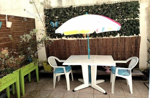 einen weißen Tisch mit Stühlen und einem Sonnenschirm in der Unterkunft Près Gare T2 42m2 avec jardinet-terrasse 10m2 in Angoulême