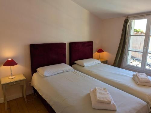 zwei Betten in einem Schlafzimmer mit zwei Lampen und einem Fenster in der Unterkunft Gîte familial avec piscine chauffée, jardin privé et équipements bébé en pleine propriété viticole. - FR-1-653-18 in Saint-Cybardeaux