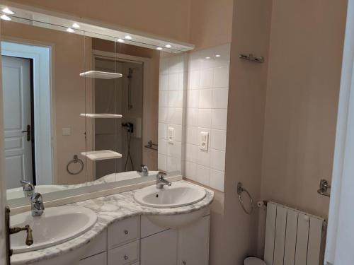 ein Badezimmer mit zwei Waschbecken und einem großen Spiegel in der Unterkunft Gîte familial avec piscine chauffée, jardin privé et équipements bébé en pleine propriété viticole. - FR-1-653-18 in Saint-Cybardeaux