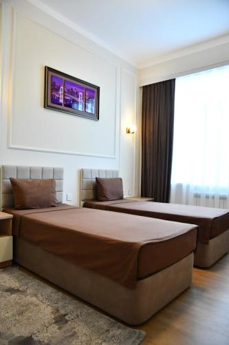 two beds in a hotel room with a tv on the wall at Park Naftalan Sanatoriya Kompleksi in Naftalan