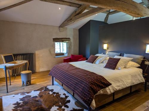 a bedroom with a large bed and a desk at Prieuré restauré avec jardin, charme ancien et commodités modernes, près de l’église à Beaulieu - FR-1-653-145 in Beaulieu-sur-Sonnette