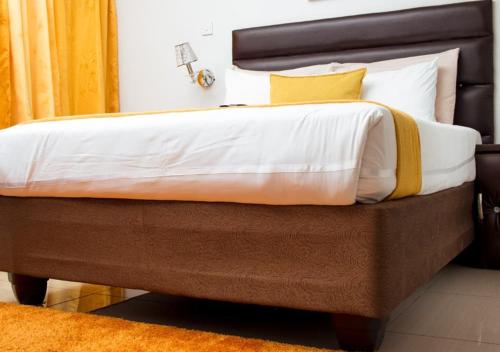 a bedroom with a large bed with white and yellow pillows at Fanky Hotel in Palatswe