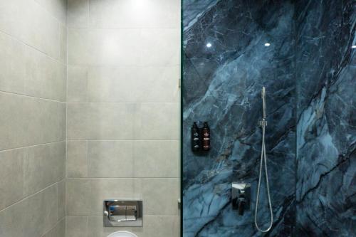 a bathroom with a shower with a marble wall at TheMirell Hôtel Dakhla in Oulad Akkou