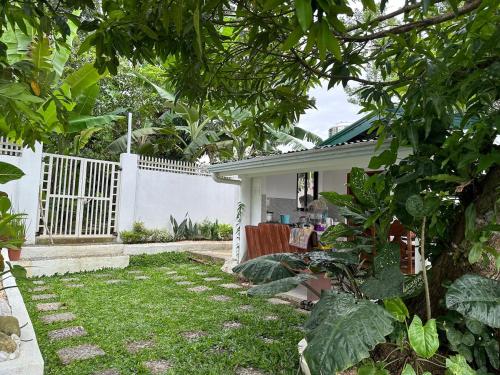 a garden with a house with a white fence at Cozy Skyview Villa in Lopez Quezon! in Lopez