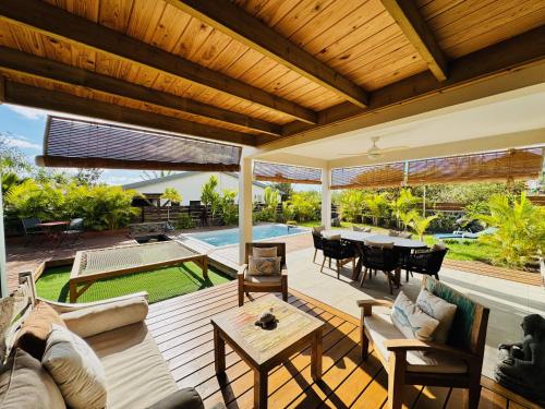 an outdoor living room with a wooden ceiling and a table at Villa Parenthèse - Piscine & Bungalow - 8 Pers in Trois Bassins