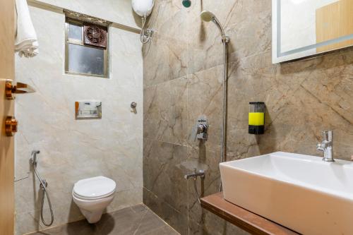 a bathroom with a white sink and a toilet at Hotel Mint in Thane
