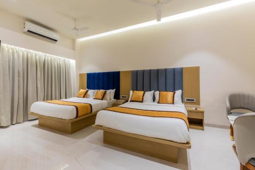 a hotel room with two beds and a chair at Hotel Mint in Thane