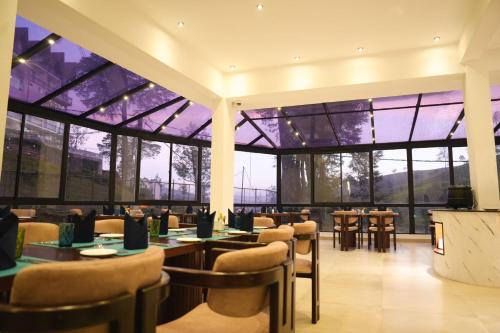 un restaurant avec des tables et des chaises et de grandes fenêtres dans l'établissement Montagna Luxury Hotel, à Nuwara Eliya