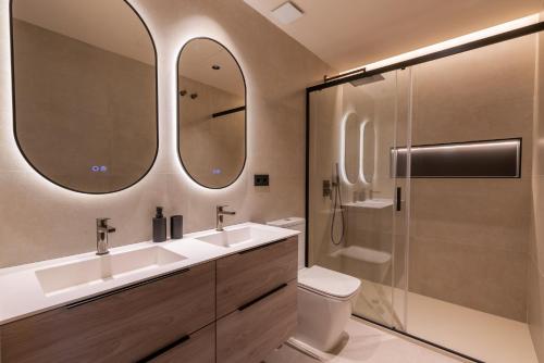 a bathroom with two sinks and a shower at Suite Plaza Nueva in Seville
