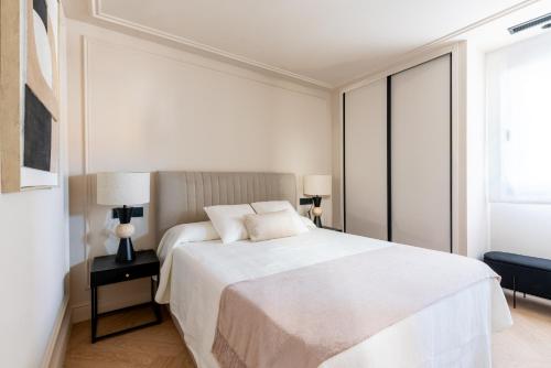 a bedroom with a large white bed and a window at Suite Plaza Nueva in Seville