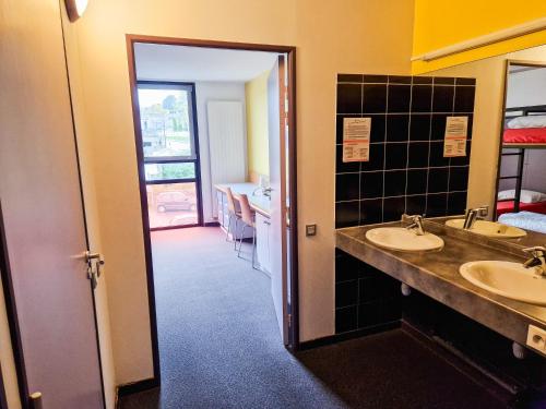 La salle de bains est pourvue de 2 lavabos et d'une porte menant à une chambre. dans l'établissement Auberge de Jeunesse de Morlaix, à Morlaix
