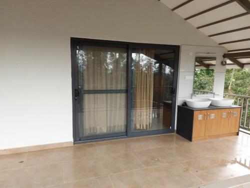 a bathroom with two sinks and sliding glass doors at GM Farm Mountain View Homestay in Avathi