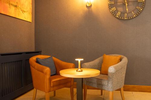 two chairs and a table with a clock on the wall at Great National Ballykisteen Golf Hotel in Tipperary