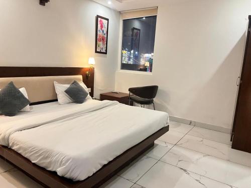 ein Schlafzimmer mit einem Bett und einem Stuhl und einem Fenster in der Unterkunft Hotel Park land in Zirakpur