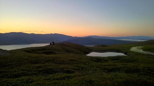 a group of people standing on a hill with a lake at Bustad in Larseng
