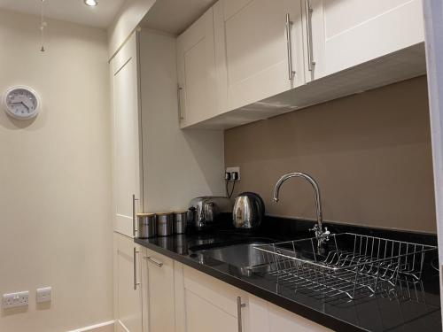 een keuken met witte kasten en een spoelbak bij Moat House 6 in Fort Augustus