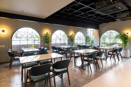 un restaurante con mesas, sillas y ventanas en Champion Prime-My Downtown Hotel, en Udaipur