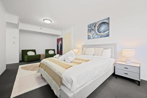 ein weißes Schlafzimmer mit einem großen Bett und einer Couch in der Unterkunft The Relaxation CBD w Parking Desk Gym Pool in Sydney