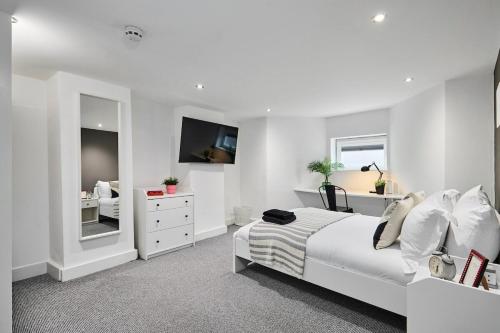 a white bedroom with a bed and a tv at Kendal Lane Apartments in Leeds
