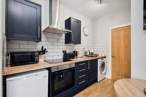 a kitchen with black cabinets and a washer and dryer at Kendal Lane Apartments in Central Station