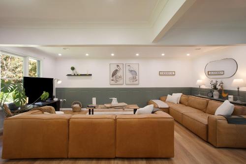 a living room with two brown couches and a tv at Highlands Heart Cottage in Bowral