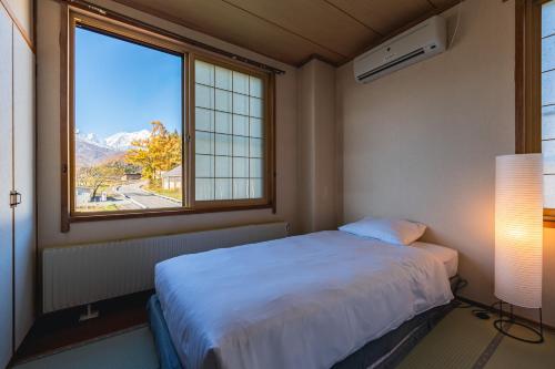een slaapkamer met een bed en een groot raam bij Wakata Lodge Hakuba - 2025 Upgrade in Hakuba