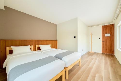 a bedroom with a large white bed and wooden floors at The Lobs Brand New, 4 bedroom, 3 bath, 4 toilet, 8 min to Rusutsu, 7-11, bus at door in Kimobetsu