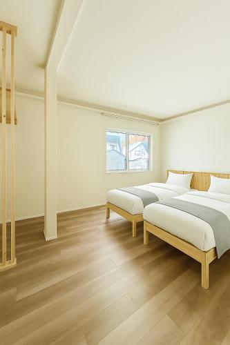 two beds in a white room with wooden floors at The Lobs Five, Brand New, 4 bedroom, 3 bath, 4 toilet, 8 min to Rusutsu, 7-11, bus at door in Kimobetsu